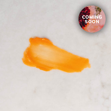 Close-up of a smooth orange balm swatch of Boswellia Rose Eye Balm spread on a light surface, with a soft, creamy texture and a “Coming Soon” badge in the corner.