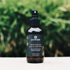 Bottle of Annmarie Sweetgrass Hair & Body Mist with a green blurred background