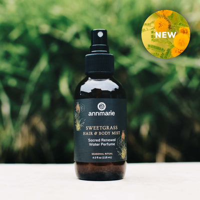 Bottle of Annmarie Sweetgrass Hair & Body Mist with a green blurred background and a NEW emblem